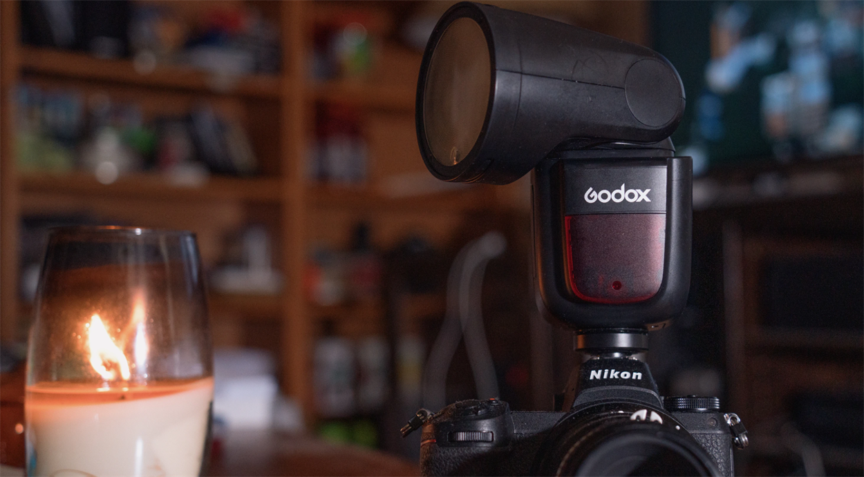 Накамерний спалах Godox V1 встановлений у гарячий башмак камери Nikon при зйомці в інтер'єрі з теплим фоновим світлом.